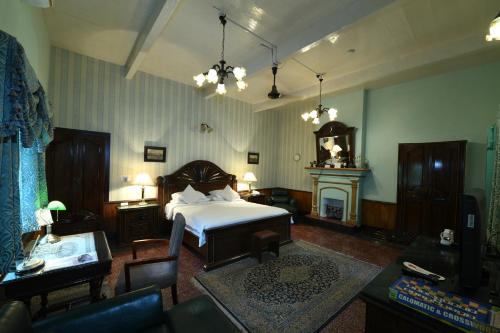 a living room with a bed and a fireplace at WelcomHeritage Judges Court in Kangra