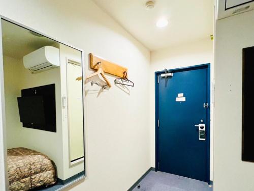 a room with a mirror and a blue door at Station Business Hotel Tenshukaku in Hitoyoshi