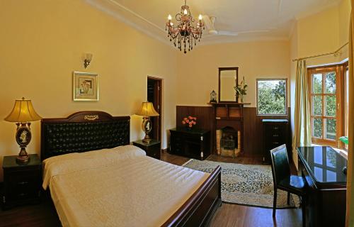 a bedroom with a bed and a chandelier at WelcomHeritage Judges Court in Kangra