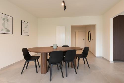 a dining room with a wooden table and black chairs at Cozy Seaside Apartment in Ostend