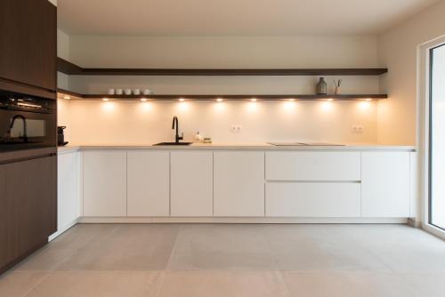 a kitchen with white cabinets and a sink at Cozy Seaside Apartment in Ostend