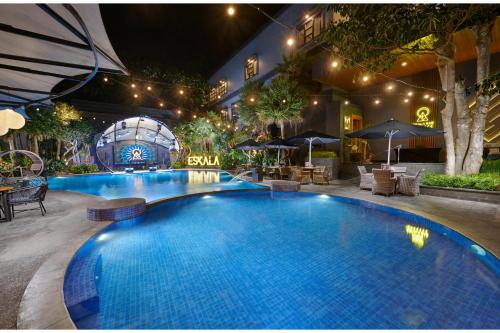 a large swimming pool in a courtyard at night at Aston Inn Batu in Batu