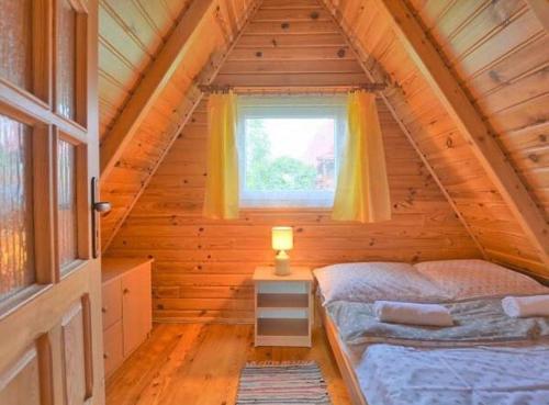 ein Schlafzimmer in einer Blockhütte mit einem Bett und einem Fenster in der Unterkunft Domki WiliCamp in Polańczyk