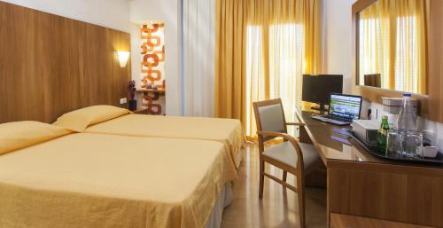 a hotel room with two beds and a desk with a computer at Leto Boutique Hotel Agrinio in Agrinion