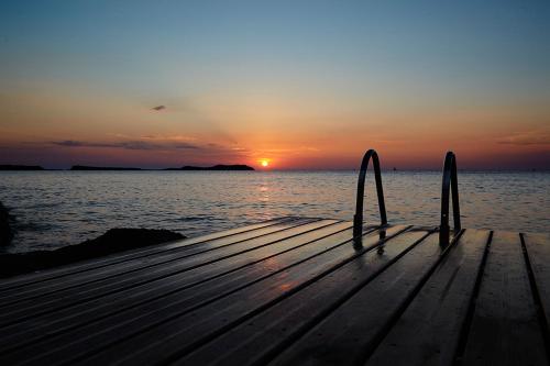 a wooden pier with the sun setting over the water at Apartamentos Mar i Vent in San Antonio