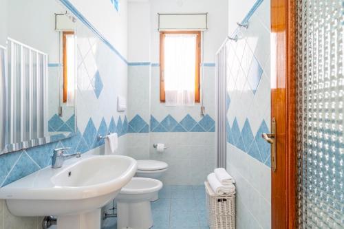 Il Rosmarino في باري ساردو: حمام ازرق وابيض مع مغسلة ومرحاض