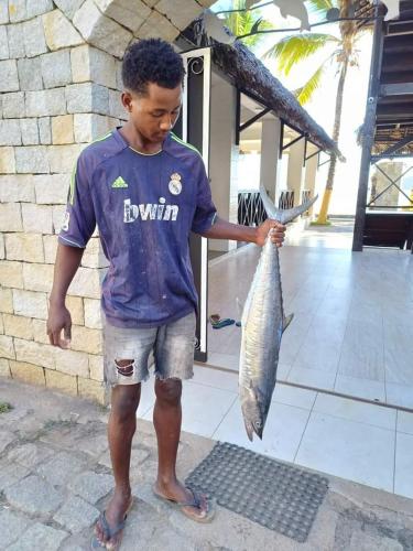 a young boy holding a fish in his hand at Ô Bleu Azur in Antsatrakolo