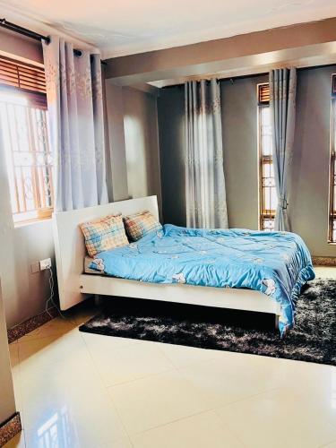 una camera da letto con un letto con lenzuola blu e finestre di Magical suite a Kampala