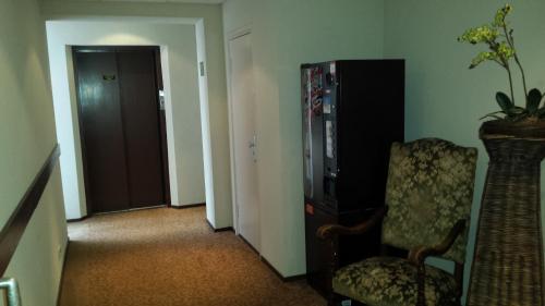 a living room with a chair and a refrigerator at Hotel Wilhelmina in Venlo