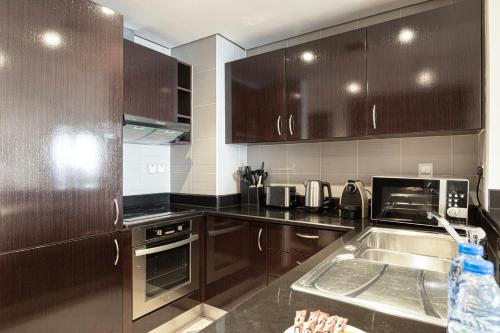 a kitchen with dark brown cabinets and a sink at Luxury Apartments in Anantara Resort with Stunning Burj AlArab & Sea Views in Dubai