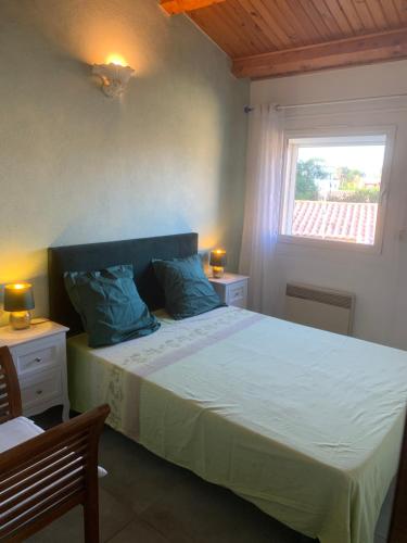 une chambre avec un lit avec des oreillers bleus et une fenêtre dans l'établissement grande villa piscine Marseillan plage cap agde, à Marseillan