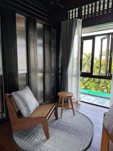 a room with a chair and a stool and a window at rongmai mahachai cafe and stay in Samut Sakhon