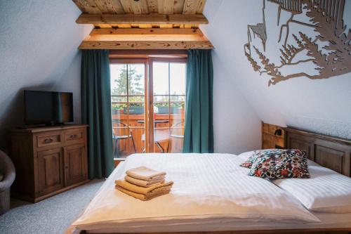 a bedroom with a bed with a television and a balcony at Wellness Penzion u Michala in Zuberec