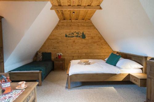 a attic room with a bed and a bench and a table at Wellness Penzion u Michala in Zuberec