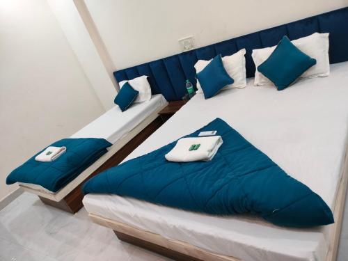two beds in a room with blue and white pillows at Rudransh Guest House in Ujjain