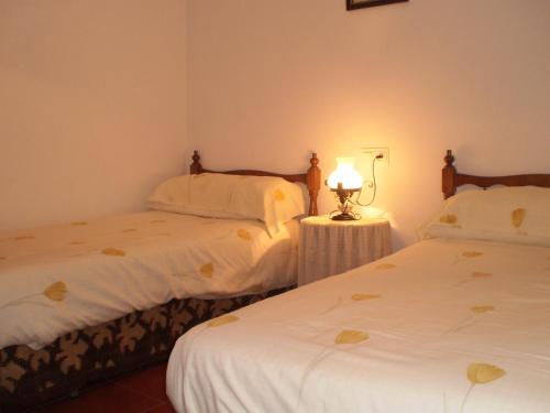ビニュエラにあるLa Atalaya de Los Romanesのベッドルーム1室(ベッド2台、テーブルの上にランプ付)