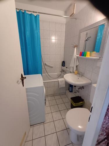 a bathroom with a blue shower curtain and a toilet and sink at SUITE Top View & City Alex 4 rooms 2 bathrooms 1 kitchen in Berlin