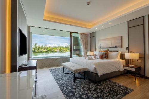 a bedroom with a large bed and a large window at ANGSANA Oceanview apartments with jacuzzi in Laguna area in Bang Tao Beach
