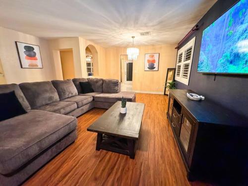 a living room with a couch and a large flat screen tv at Spacious 4BR Fam Retreat King Bed WIFI And Parking in Las Vegas