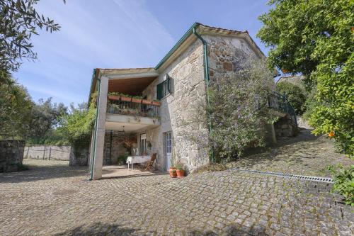 an old stone house with a balcony on a brick driveway at Authentic apartment in rural area in Pindo
