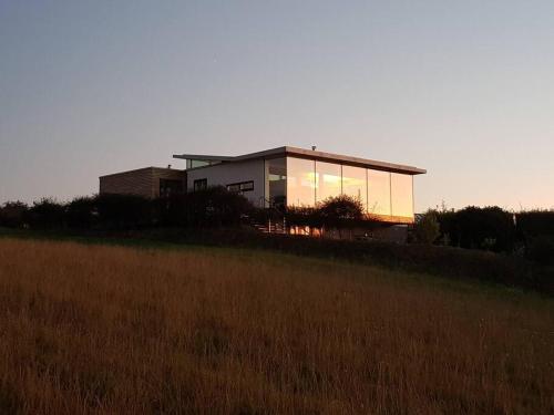 a house sitting on top of a grass field at Luminaire hosted accommodation in Guernsey