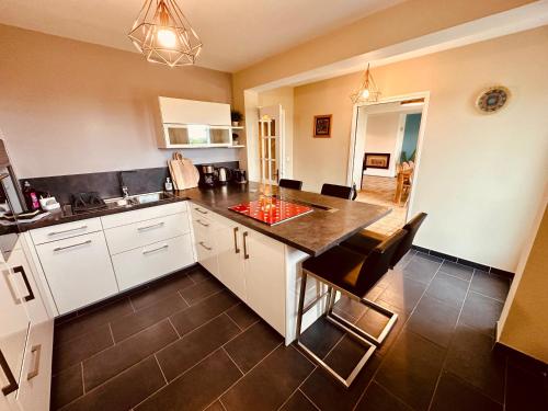 une cuisine avec des armoires blanches et un comptoir noir dans l'établissement La Tanière, à Tardinghen