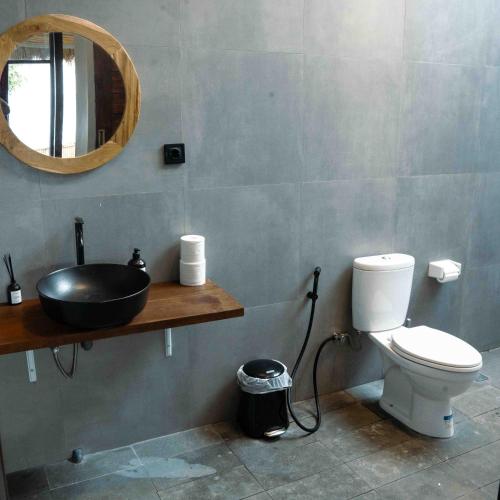 a bathroom with a sink and a toilet and a mirror at Treeland villa in Nusa Penida