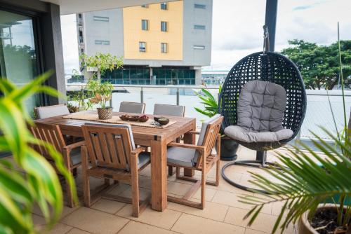 a patio with a wooden table and a chair at Barefoot Beach Apartment Darwin Waterfront in Darwin