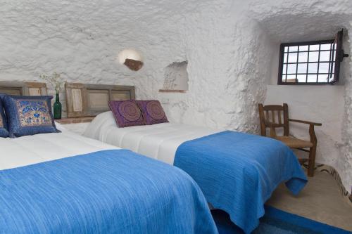 a bedroom with two beds and a chair at Balcones de Piedad in Los Balcones