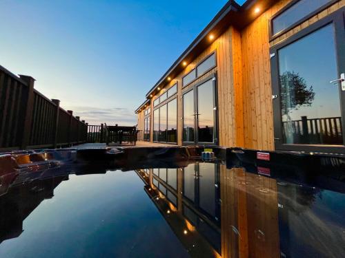 a building with a reflection in a pool of water at Forest Hills Holidays in Coleford