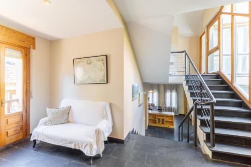 a living room with stairs and a white chair at Casa Rural Cantueso 1 in La Matilla