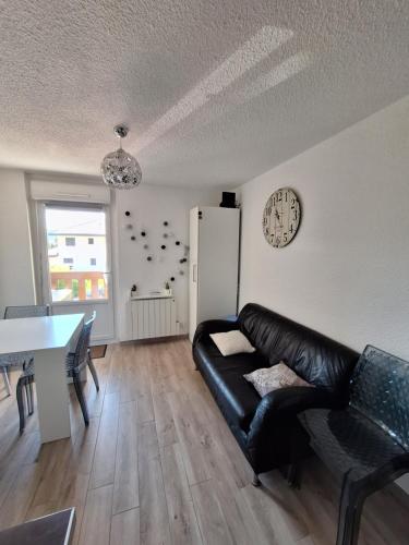 a living room with a black leather couch and a table at Studio rénové confort meublé 3 étoiles - Les Crêtets in Les Rousses