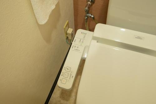 a toilet with a remote control next to a wall at HOTEL AARON通天東 in Osaka