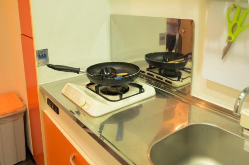two frying pans on a stove in a kitchen at HOTEL AARON通天東 in Osaka