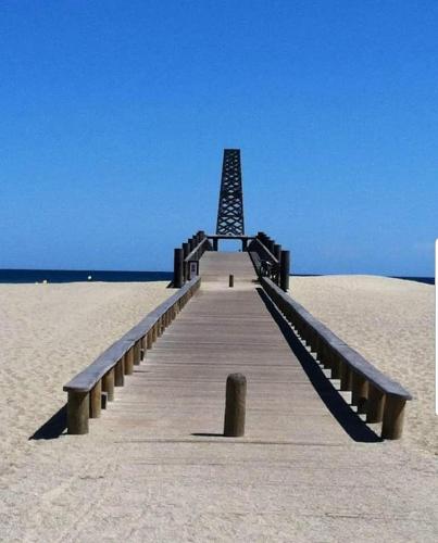 une jetée en bois au milieu de la plage dans l'établissement Maison de vacances les pieds dans l'eau Port Leucate, à Leucate