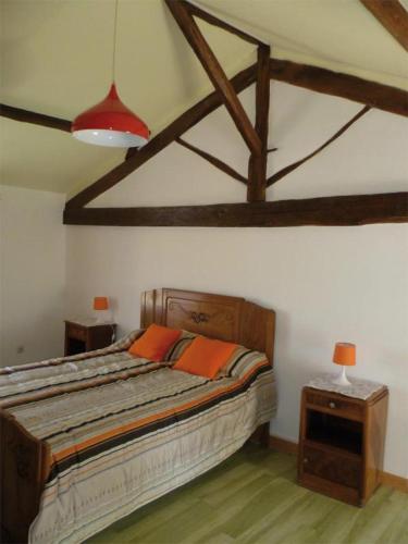 a bedroom with a large bed with two orange pillows at Franmélie in Valence en Poitoux