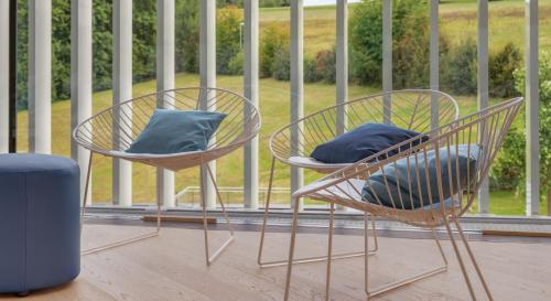 two chairs with blue pillows sitting on a balcony at Hotel Stoiser in Loipersdorf bei Fürstenfeld
