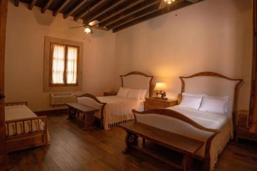 Un dormitorio con dos camas y una mesa y una ventana. en Hacienda Maria Trinidad, en Valle de Guadalupe