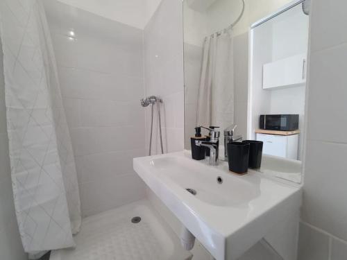 une salle de bain blanche avec un lavabo et un miroir dans l'établissement Appartement Cosy et Calme - Centre historique, à Montpellier