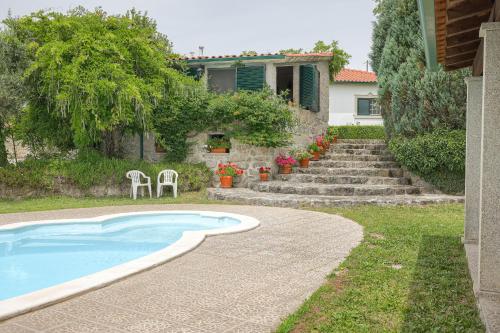 a swimming pool with two chairs and a house at Authentic apartment in rural area in Pindo