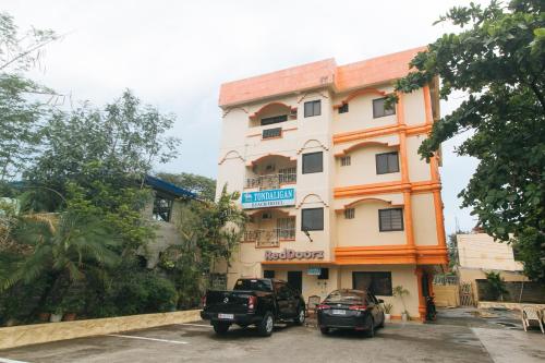 a building with two cars parked in front of it at RedDoorz @ Tondaligan Beach Hotel in Dagupan