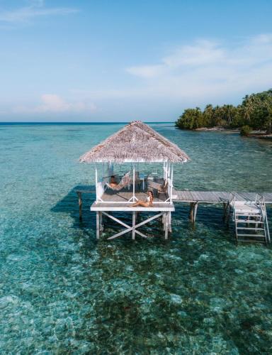 an island with two people laying on a pier in the water at Reconnect - Private Island Resort & Dive Center Togean - Buka Buka Island in Ampana