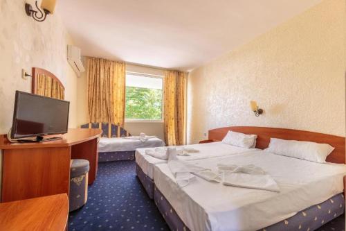 a hotel room with two beds and a television at Хотел Черноморец in Chernomorets