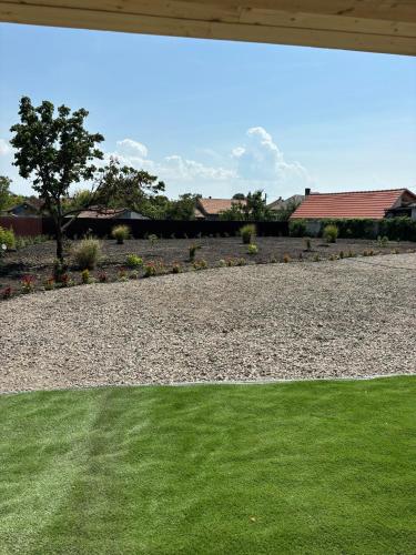 a yard with green grass and a gravel driveway at Relax Vendégház Tisza-tó in Poroszló