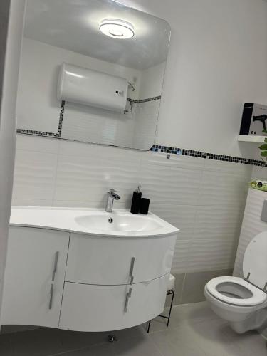 a white bathroom with a sink and a toilet at Relax Vendégház Tisza-tó in Poroszló
