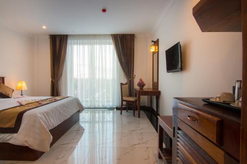a hotel room with a bed and a desk and a television at Glorious Hotel in Kompong Thom