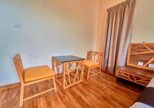 a room with a table and chairs and a bed at AJ Gable Clouds Ooty by VOYE HOMES - Serene Stay Near Avalanche Emerald Lake in Ooty