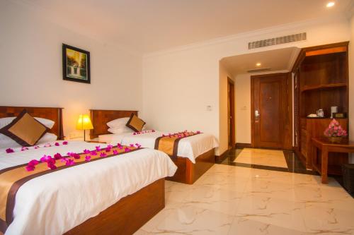 a hotel room with two beds with pink flowers on them at Glorious Hotel in Kompong Thom