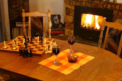 un tablero de ajedrez y dos copas de vino en una mesa con chimenea en Guesthouse KaraIvan, en Arda