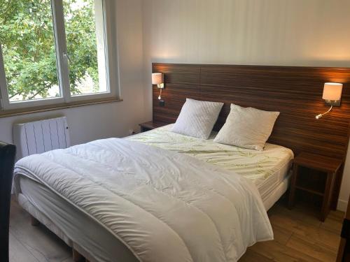 une chambre avec un grand lit avec une tête de lit en bois dans l'établissement Au Petit Thalassa, à Boulogne-sur-Mer